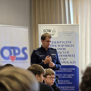 zdjęcie przedstawia policjanta rozmawiającego z uczniami