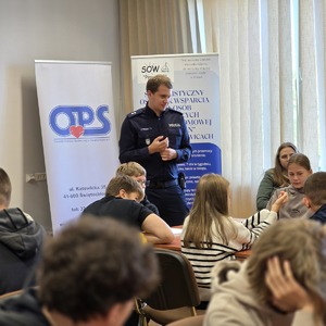 zdjęcie przedstawia policjanta rozmawiającego z uczniami