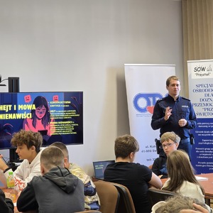 zdjęcie przedstawia policjanta rozmawiającego z uczniami
