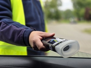 zdjęcie przedstawia policjanta z alkomatem