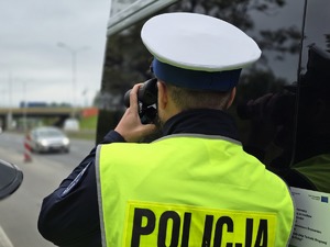 zdjęcie przedstawia policjanta patrzącego przez lornetkę