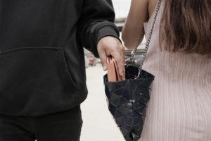 zdjęcie przedstawia mężczyznę wyciągającego rzeczy z torebki kobiety