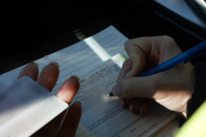zdjęcie przedstawia policjanta wypisującego mandat