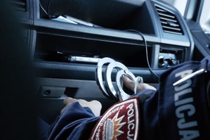 zdjęcie przedstawia policjanta trzymającego kajdanki