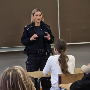 zdjęcie przedstawia policjantkę w klasie rozmawiająca z uczniami