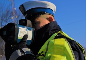 zdjęcie przedstawia policjanta mierzącego prędkość