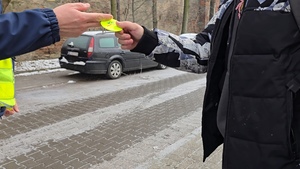 zdjęcie przedstawia policjanta rozdającego odblaski