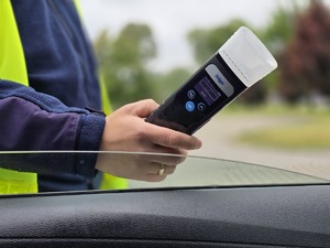 zdjęcie przedstawia policjanta trzymającego urządzenie do badania trzeźwości