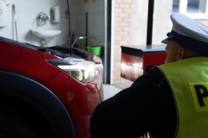 zdjęcie przedstawia policjanta sprawdzającego oświetlenie pojazdu