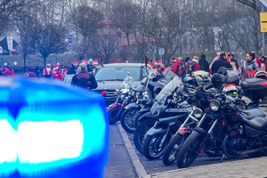 zdjęcie przedstawia zbliżenie sygnał policyjny a w tle uczestnicy parady