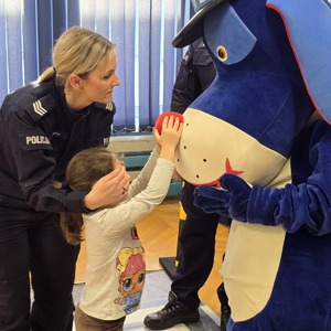 zdjęcie przedstawia policjantkę, dzieci i maskotkę psa sznupka