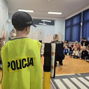 zdjęcie przedstawia chłopca w kamizelce odblaskowej z napisem policja