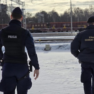 zdjęcie przedstawia policjanta i funkcjonariusza straży ochrony kolei podczas patrolu na torowisku
