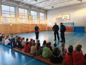 zdjęcie przedstawia policjantów i strażnika miejskiego na spotkaniu z pierwszoklasistami