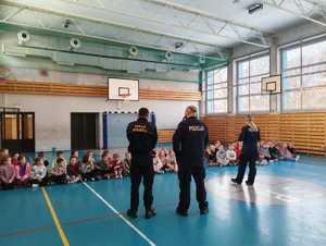 zdjęcie przedstawia policjantów i strażnika miejskiego na spotkaniu z pierwszoklasistami