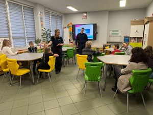 zdjęcie przedstawia policjantkę rozmawiającą z dziećmi w szkole