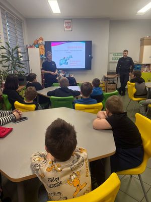 zdjęcie przedstawia policjantkę rozmawiającą z dziećmi w szkole