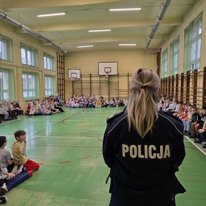 zdjęcie przedstawia policjantkę rozmawiającą z dziećmi na sali gimnastycznej