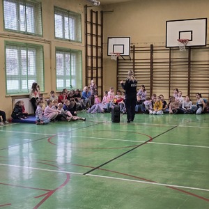 zdjęcie przedstawia policjantkę rozmawiającą z dziećmi na sali gimnastycznej