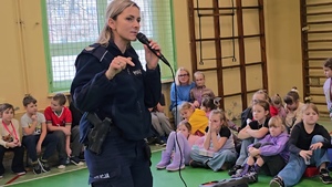 zdjęcie przedstawia policjantkę rozmawiającą z dziećmi na sali gimnastycznej