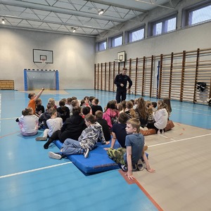 zdjęcie przedstawia policjanta rozmawiającego z dziećmi