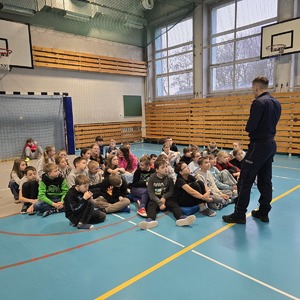 zdjęcie przedstawia policjanta rozmawiającego z dziećmi