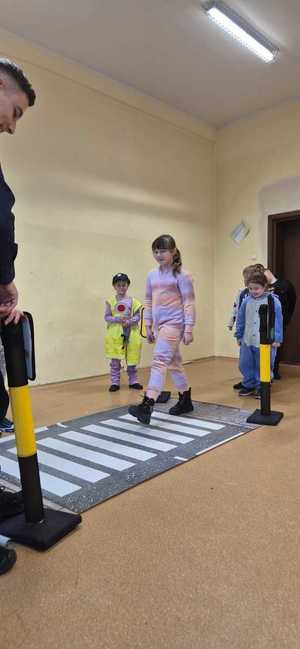 zdjęcie przedstawia policjanta rozmawiającego z dziećmi w szkole