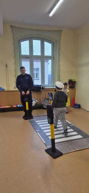 zdjęcie przedstawia policjanta rozmawiającego z dziećmi w szkole