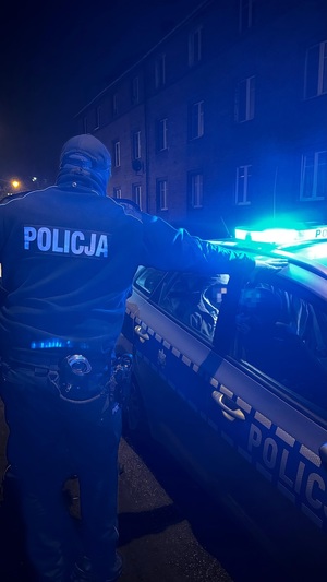 zdjęcie przedstawia policjanta przy radiowozie
