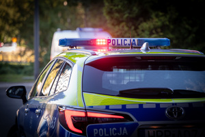 zdjęcie przedstawia radiowóz z włączonymi sygnałami