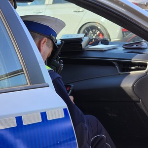 zdjęcie przedstawia policjanta wykonującego czynności na drodze