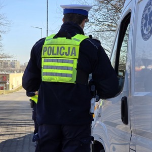 zdjęcie przedstawia policjanta wykonującego czynności na drodze