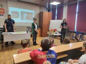 zdjęcie przedstawia mundurowych i pracownika schroniska podczas prelekcji w szkole