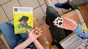 zdjęcie przedstawia dzieci trzymające ulotki i zabawkowe łapki