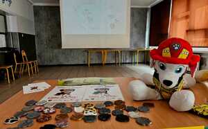 zdjęcie przedstawia materiały edukacyjne i pluszaka na tle prezentacji