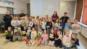 zdjęcie grupowe policjantki, strażnika miejskiego i dzieci ze szkoły