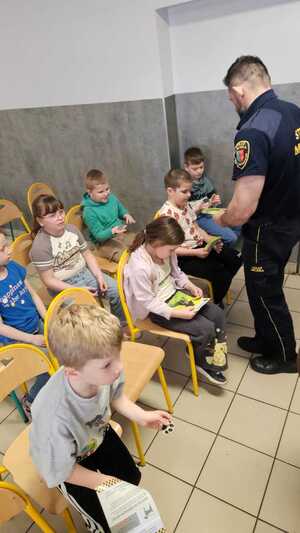 zdjęcie przedstawia strażnika miejskiego rozdającego broszury informacyjne