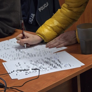 zdjęcie przedstawia kobietę podpisującą zarzuty