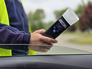 zdjęcie przedstawia policjanta z urządzeniem do badania trzeźwości