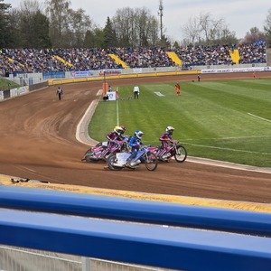 zdjęcie przedstawia zawodników żużlowych podczas wyścigu