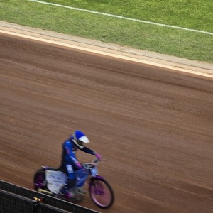 zdjęcie przedstawia zawodników żużlowych podczas wyścigu