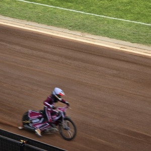 zdjęcie przedstawia zawodników żużlowych podczas wyścigu