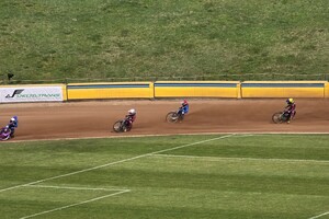 zdjęcie przedstawia zawodników żużlowych podczas wyścigu