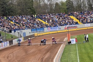 zdjęcie przedstawia zawodników żużlowych podczas wyścigu