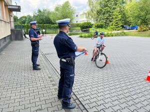 zdjęcia policjant umundurowany i dzieci podczas zdawania na kartę rowerową
