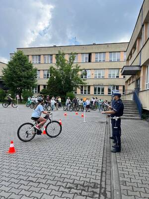 zdjęcia policjant umundurowany i dzieci podczas zdawania na kartę rowerową