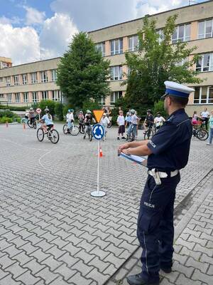 zdjęcia policjant umundurowany i dzieci podczas zdawania na kartę rowerową