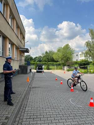 zdjęcia policjant umundurowany i dzieci podczas zdawania na kartę rowerową