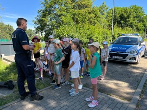 zdjęcie przedstawia policjanta rozmawiającego z dziećmi