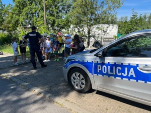 zdjęcie przedstawia policjanta rozmawiającego z dziećmi